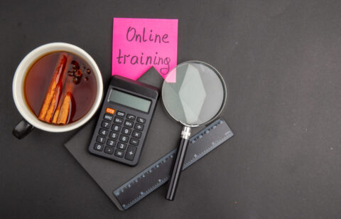 top view online training written on sticky notes pen ruler lupa calculator notepad cup of tea on dark background copy place